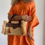 Add a unique twist to your outfit with this stunning straw handbag. Hand-embellished with pearled, sequinned silk and a bright orange pom pom. 