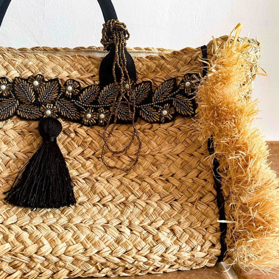 This beautiful straw purse features unique hand embellished, intricately hand-beaded yoke details and a top handle that makes it easy to carry.
