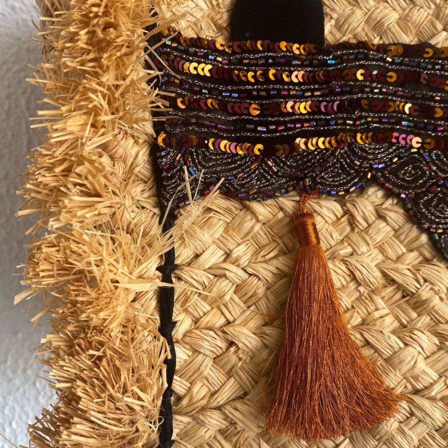 Add a unique twist to your outfit with this stunning straw handbag. Hand-embellished with pearled, sequinned silk and a bright orange pom pom. 