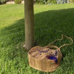 This unique bohemian-inspired Round Rattan bag crafted from natural fiber is adorned with small blue glass beads and a unique antique Afghan charm.